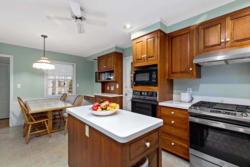 Fully equipped Cape Cod kitchen with center island, gas range, and breakfast table, ideal for family meals in Centerville.