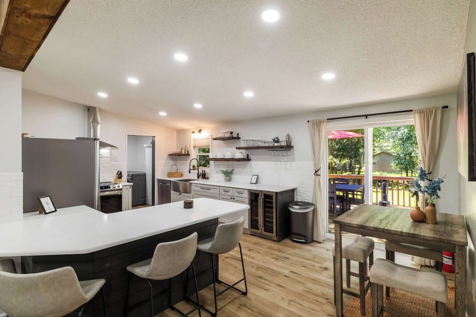 An open-concept kitchen and dining area with a bar island, wine fridge, breakfast nook, and direct deck access — the social hub of this Pocono vacation rental.