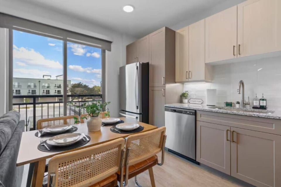 Fully equipped with stainless steel appliances, granite countertops, and a dining table set for four.