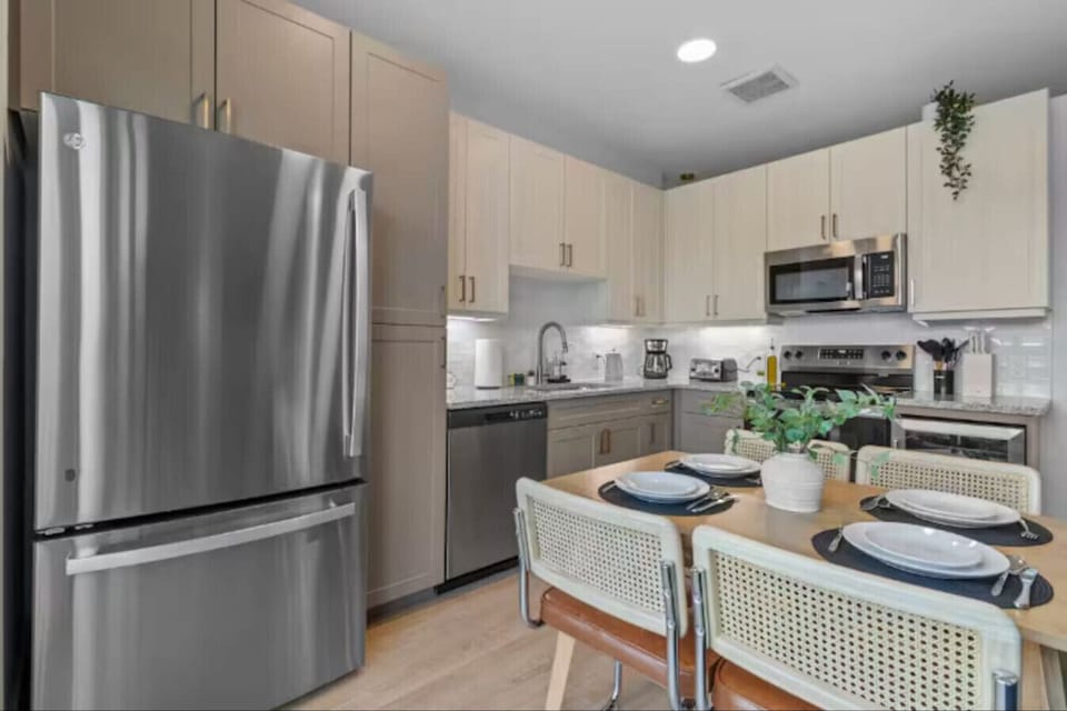 Fully equipped with stainless steel appliances, granite countertops, and a dining table set for four.