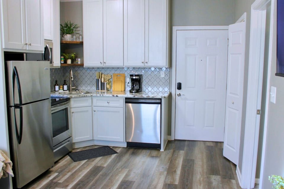Kitchen. This fully equipped space features stainless steel appliances, a patterned tile backsplash, and granite countertops