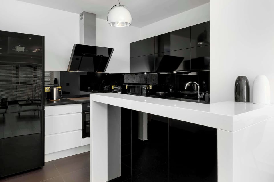 A modern kitchen with black cabinets, a white countertop, and high-end appliances, designed for functionality and style.