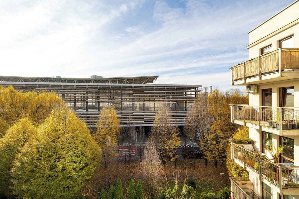Exterior view of the building with surrounding greenery, showing a modern apartment complex.