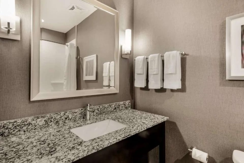 Clean bathroom with granite counter, mirror, and fresh white towels