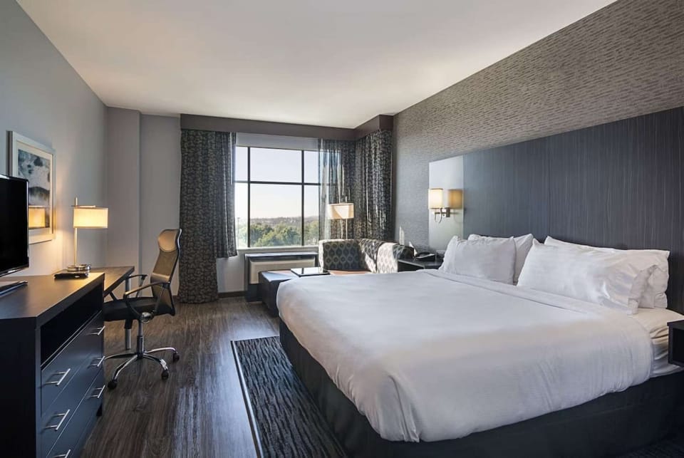 King room with desk, big window, and lounge by the bed