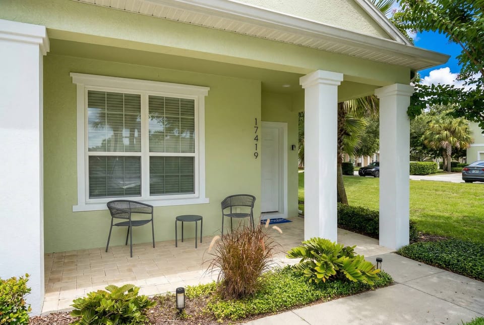 Step outside to a charming porch where two stylish metal chairs invite you to relax. The lush greenery and well-kept landscaping frame the entrance, creating a welcoming vibe that sets the tone for your stay.