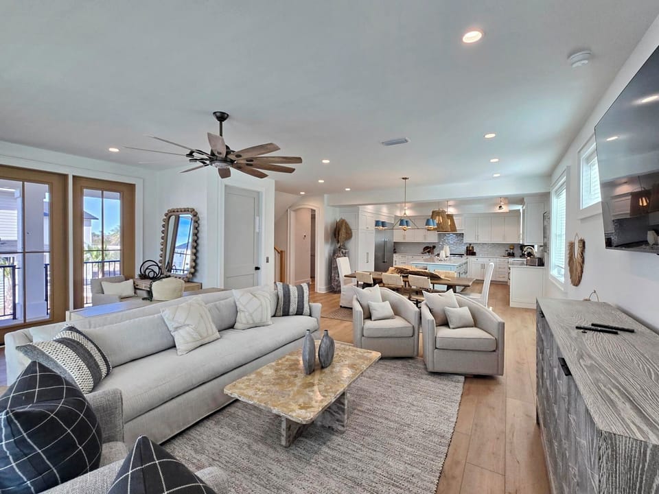 Relax in your spacious open-concept living area with plush seating, modern kitchen, and balcony access for the perfect vacation retreat.