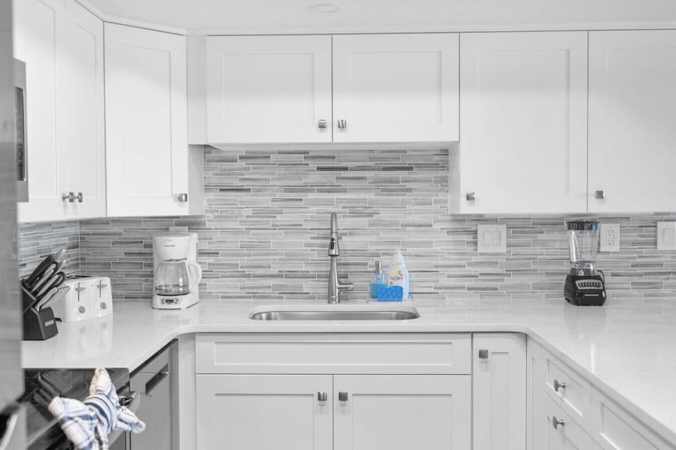 Pristine white and grey kitchen complete with a toaster, coffee maker, and a blender.
