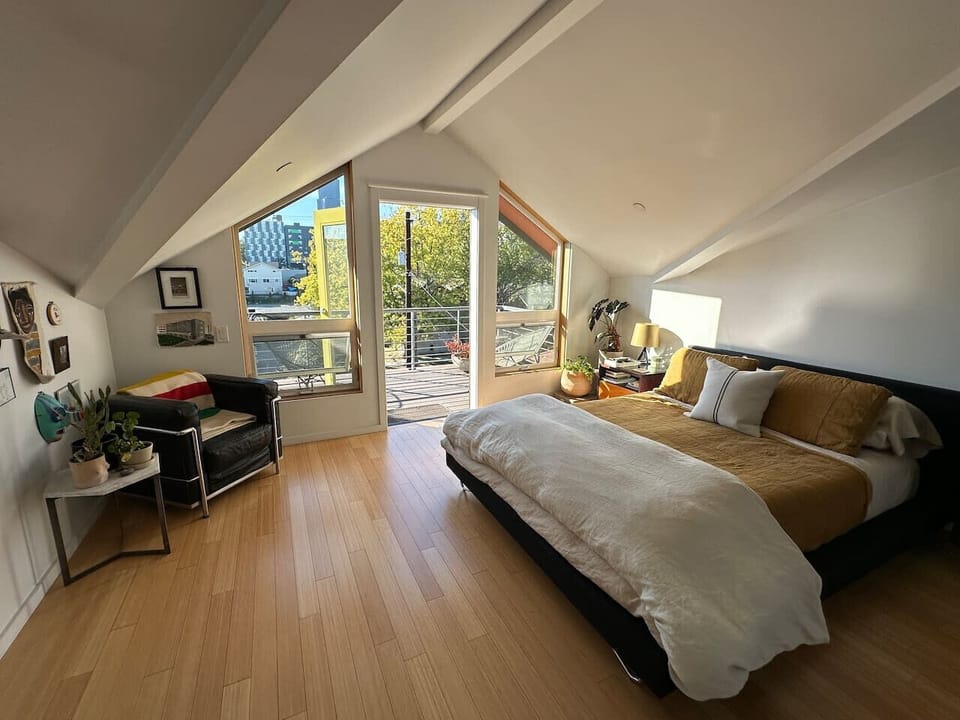Open floor plan primary bedroom with private terrace overlooking community garden, ensuite bathroom and walk-in closet with laundry.