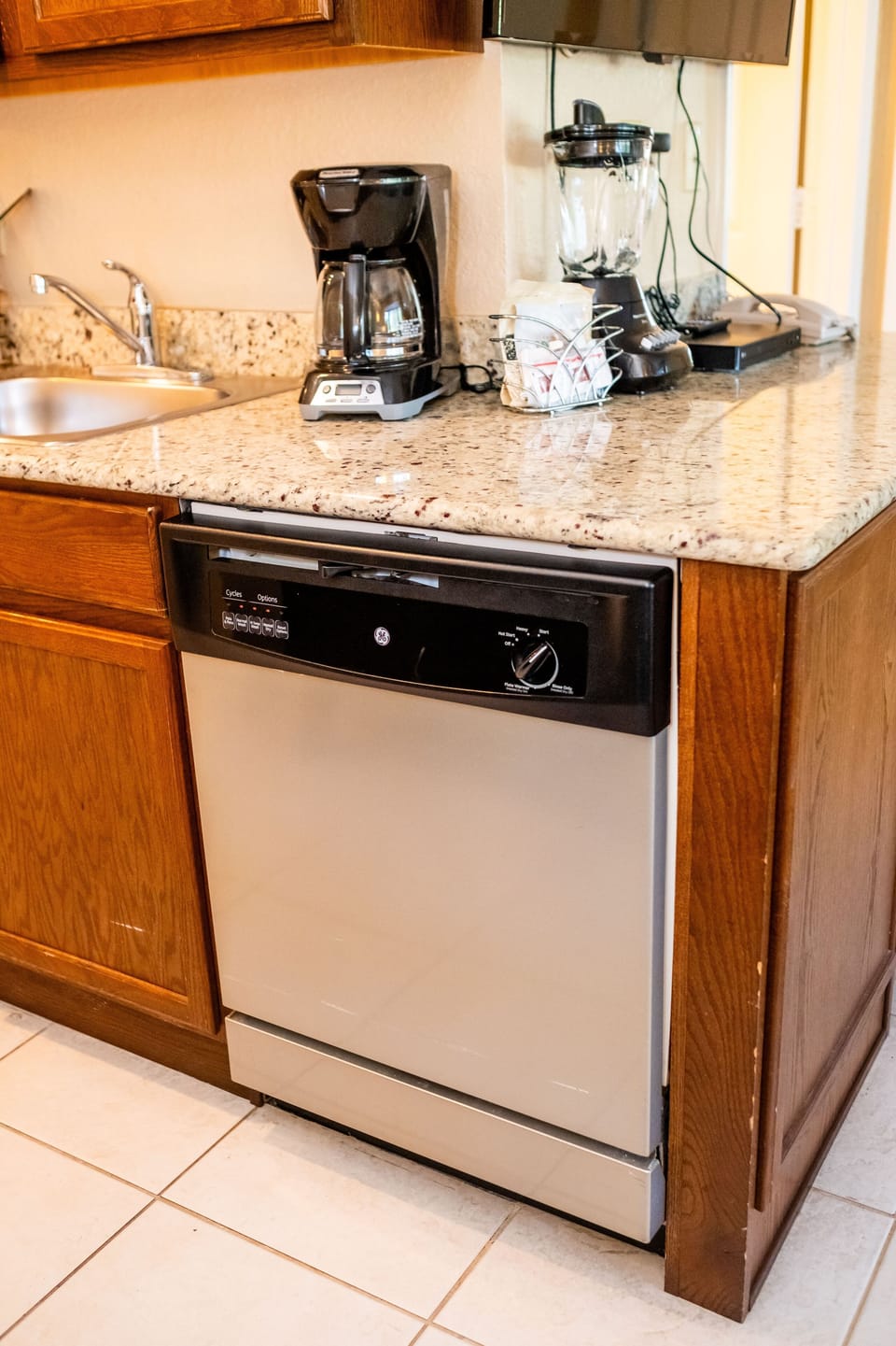 Functional kitchen corner featuring a dishwasher and coffee maker on granite counters.