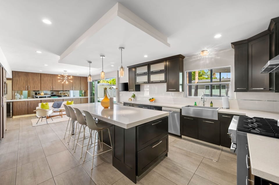 Bright, chef style kitchen with a large island, bar seating, and high end appliances. Fully stocked for cooking and entertaining, with large stacking glass doors that open directly to the pool for easy indoor outdoor living.