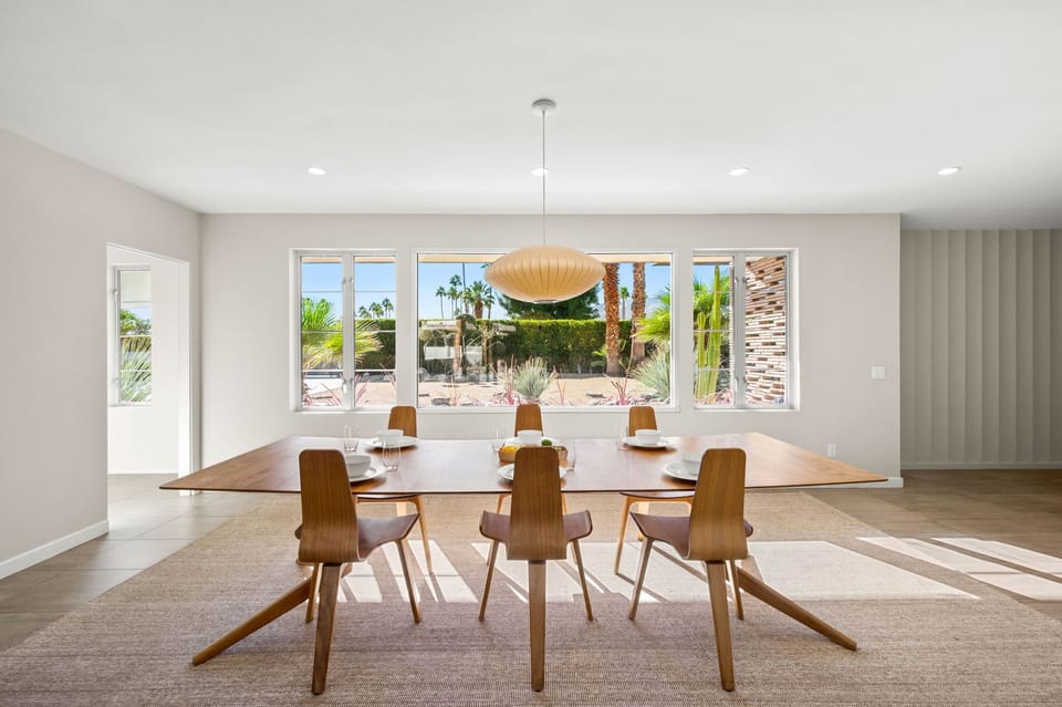 Bright, stylish dining room with seating for up to eight guests, framed by large windows and curated artwork that adds a true mid century feel. Two additional chairs are available but not pictured, making it easy to gather everyone around the table.