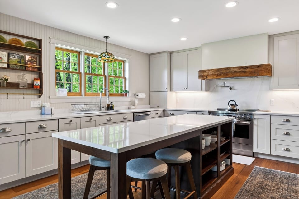 Bright farmhouse kitchen with a large island, modern appliances, and peaceful wooded views.