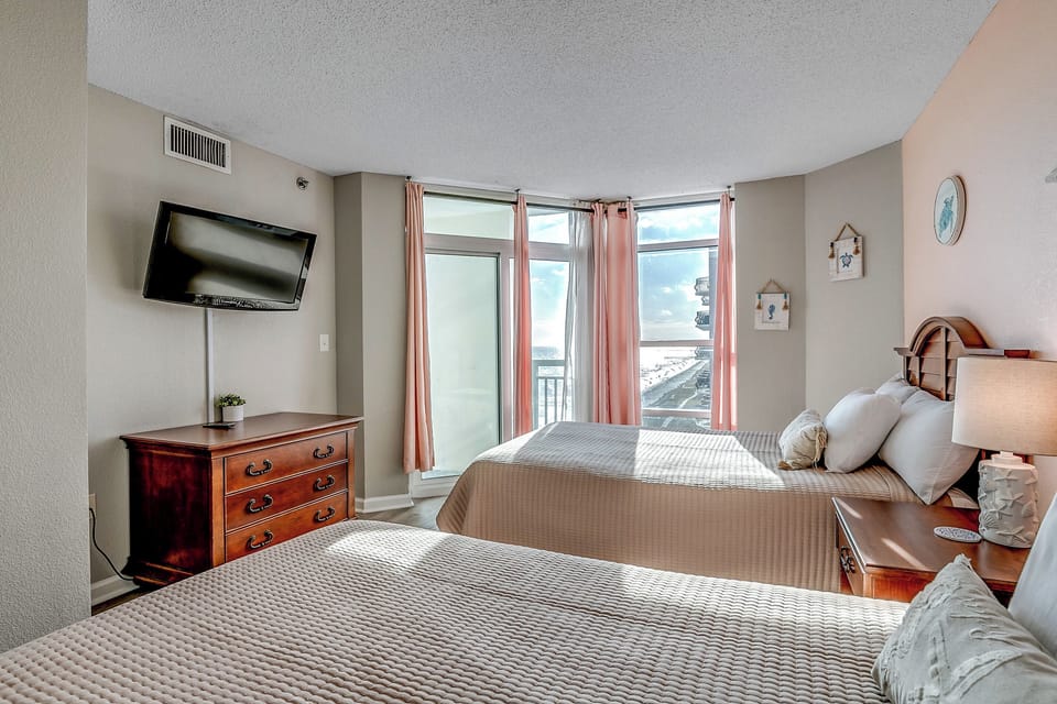 Second bedroom with two double beds, dresser storage, and flat screen TV.