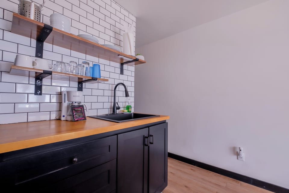 Your stylish kitchenette features warm wood counters, subway tile backsplash, and open shelving for easy meal prep.