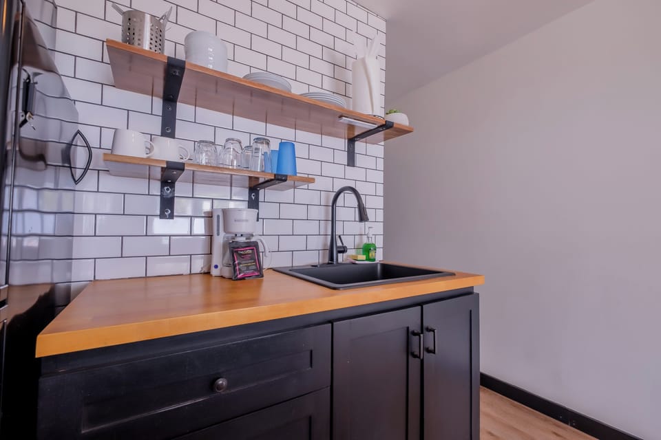 Your stylish kitchenette features warm wood countertops and subway tile backsplash, perfect for preparing morning coffee or light meals.