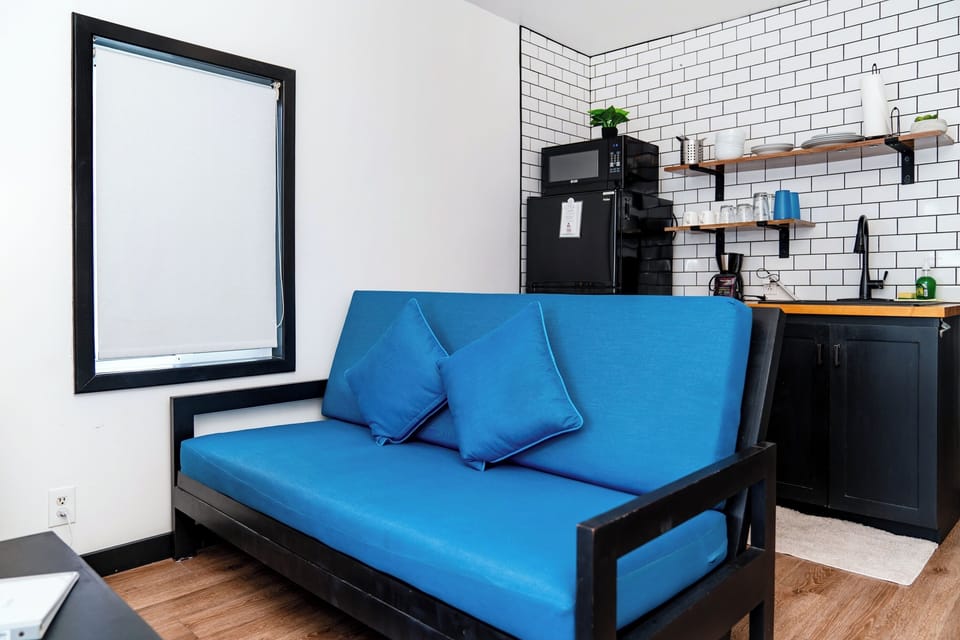 Unwind on the vibrant blue sofa (also a full futon bed) perfectly positioned near a kitchenette equipped with everything you need to feel at home during your stay.