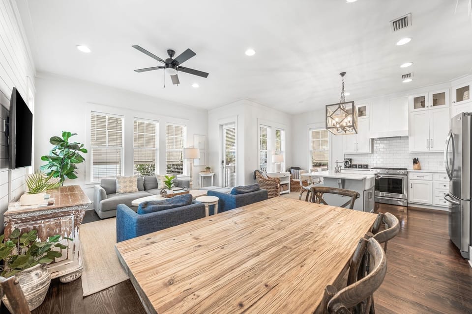 Your open-concept living space flows seamlessly from dining to kitchen, perfect for gathering around the rustic wood table.