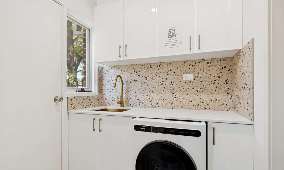 Laundry area with washing machine, sink, and built-in cabinetry.