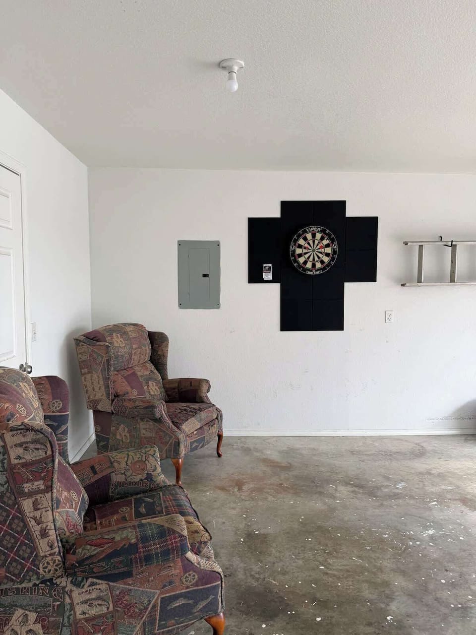 A dart board and sitting chairs have been added to turn the garage into an rainy day activity area