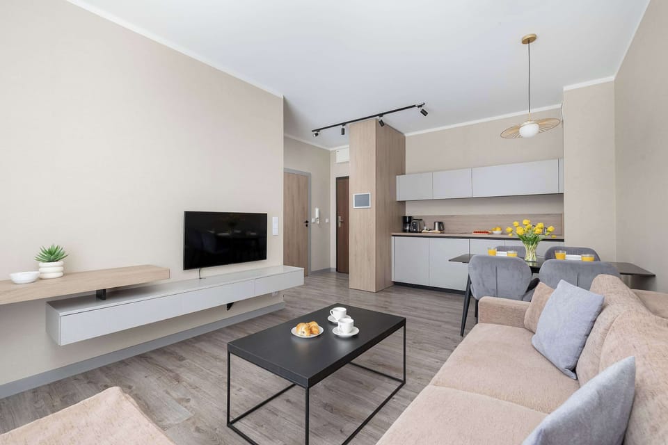 A wider perspective of the living room showing the sofa, TV, and dining area. The space is ideal for both relaxation and dining.