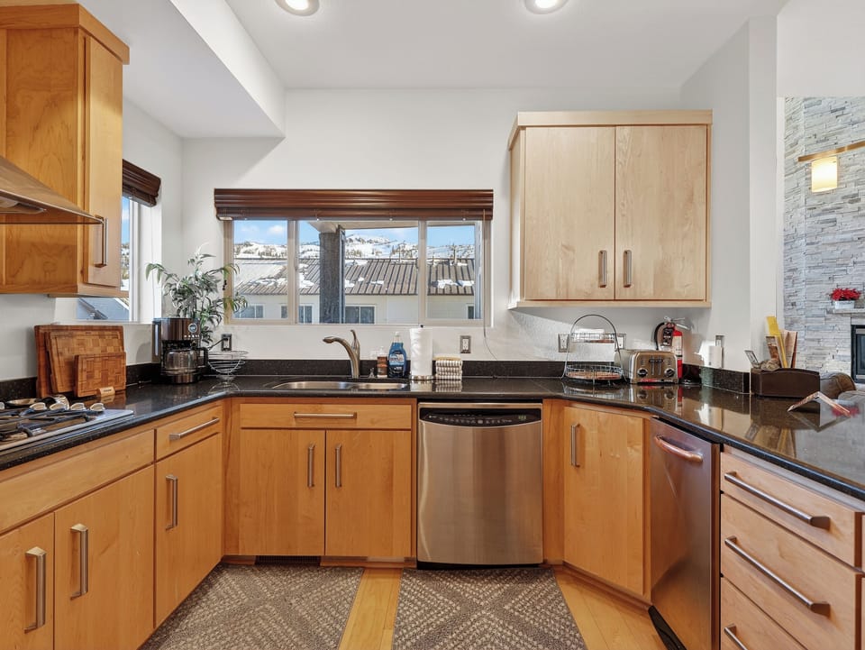 Your spacious kitchen invites culinary adventures with gleaming granite counters, stainless steel appliances, and charming rooftop views.