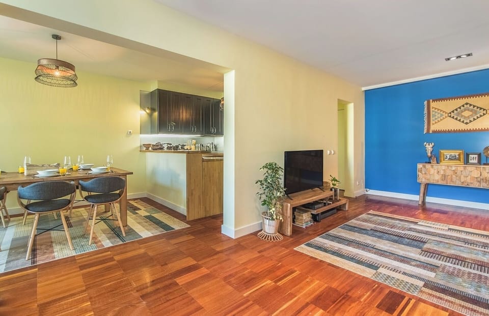 Living Room with TV that opens onto the balcony. The full length windows allow the light to brighten up the space.