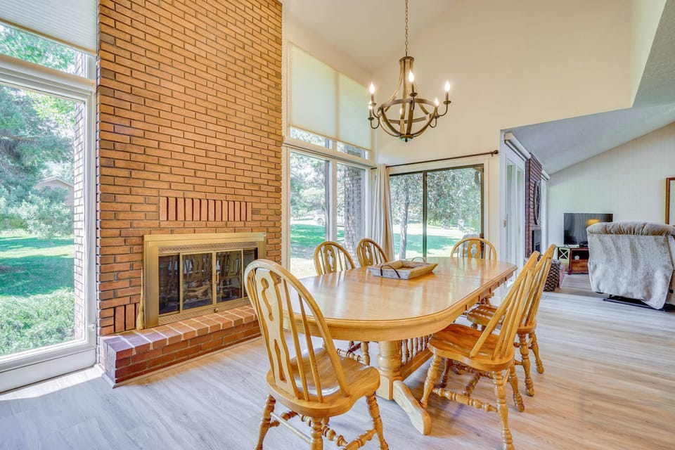 Sunlit dining area with soaring ceilings and cozy brick fireplace