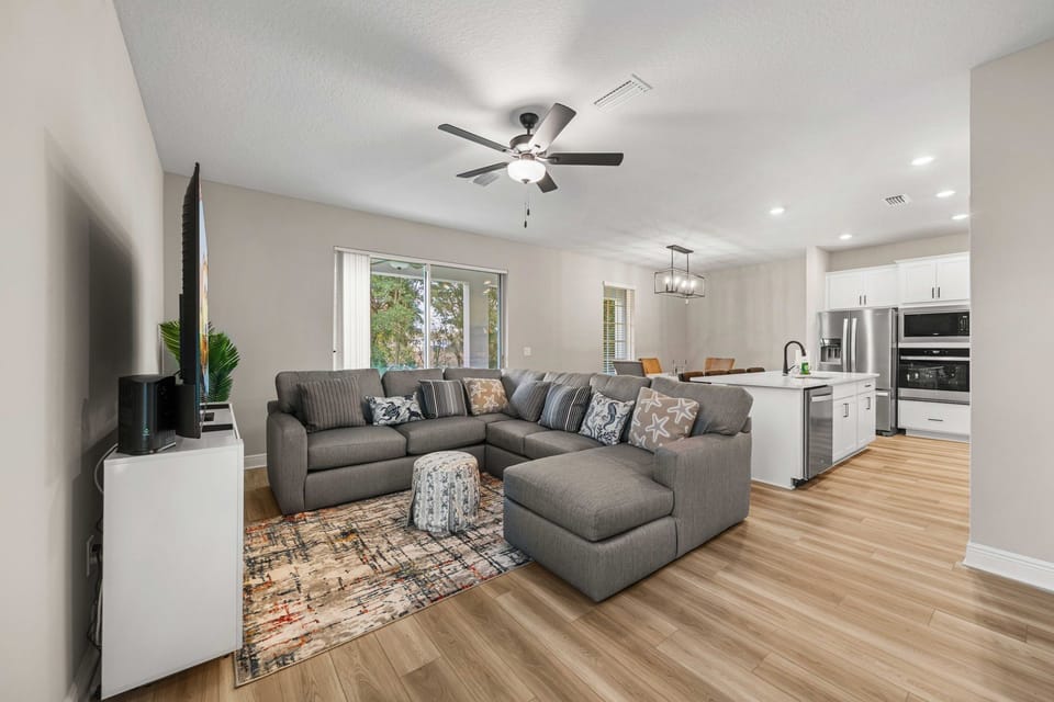 Open-concept living area with plush sectional and modern kitchen, perfect for entertaining.