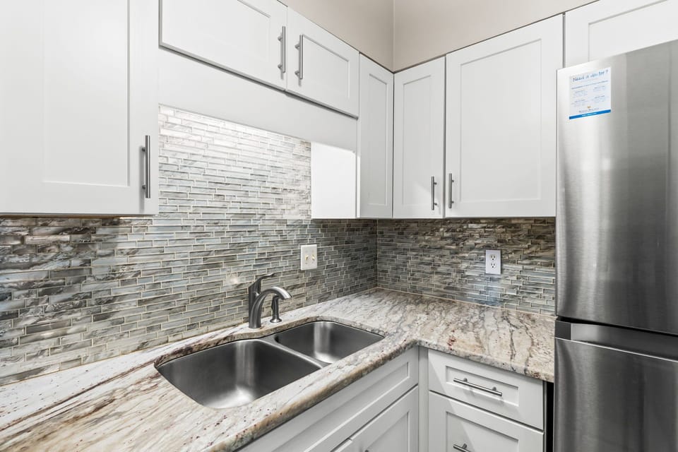 Double stainless sinks, plenty of counter space and cabinets all filled with dinnerware, drinkware and cooking utinsils.