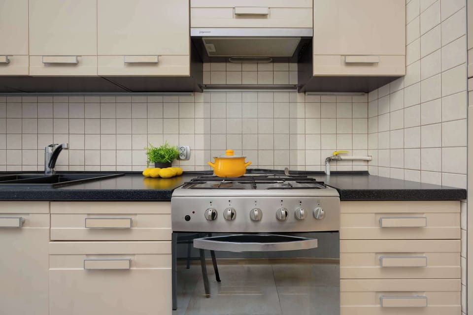Functional kitchen with light cabinetry, tiled backsplash, built-in appliances, and compact layout.