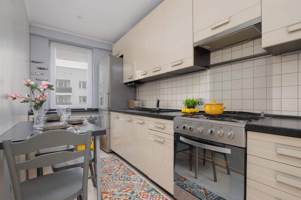Functional kitchen with light cabinetry, tiled backsplash, built-in appliances, and compact layout.