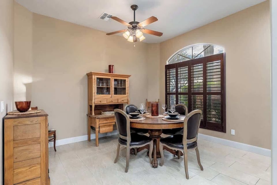 Gather around this elegant round table for memorable meals bathed in natural light from the arched window. Warm wood furnishings and a charming hutch create an inviting space perfect for your morning coffee or evening dinner.