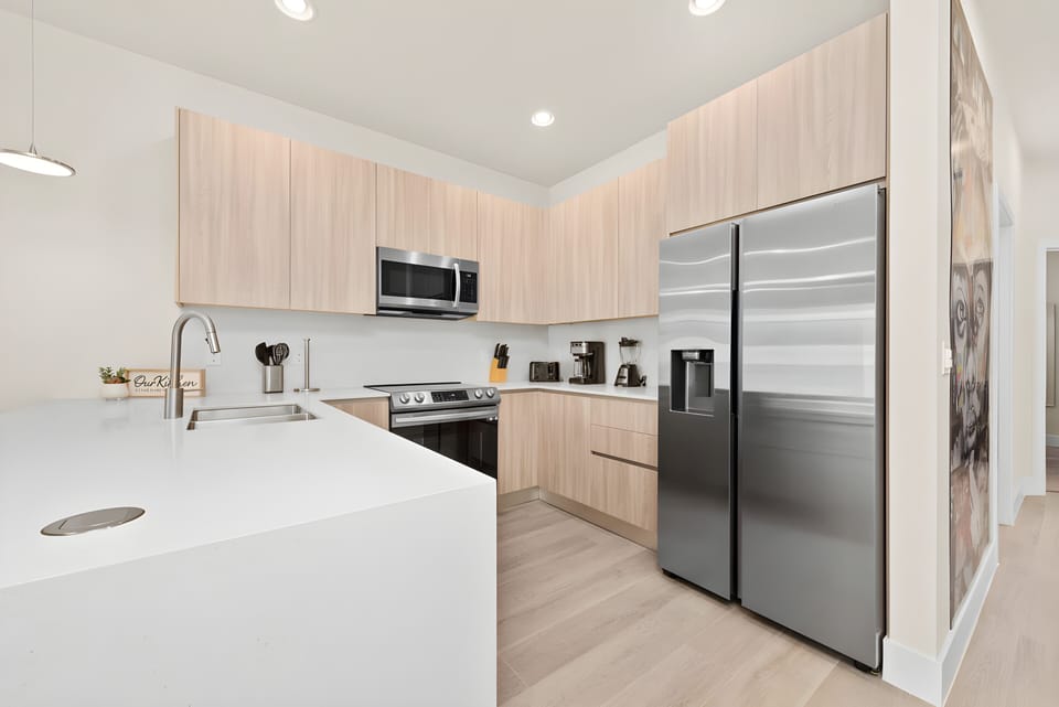 Welcome to a bright kitchen featuring light wood cabinetry and sleek stainless steel appliances that blend style and functionality. The spacious island is ideal for casual dining, creating a clean and inviting atmosphere.