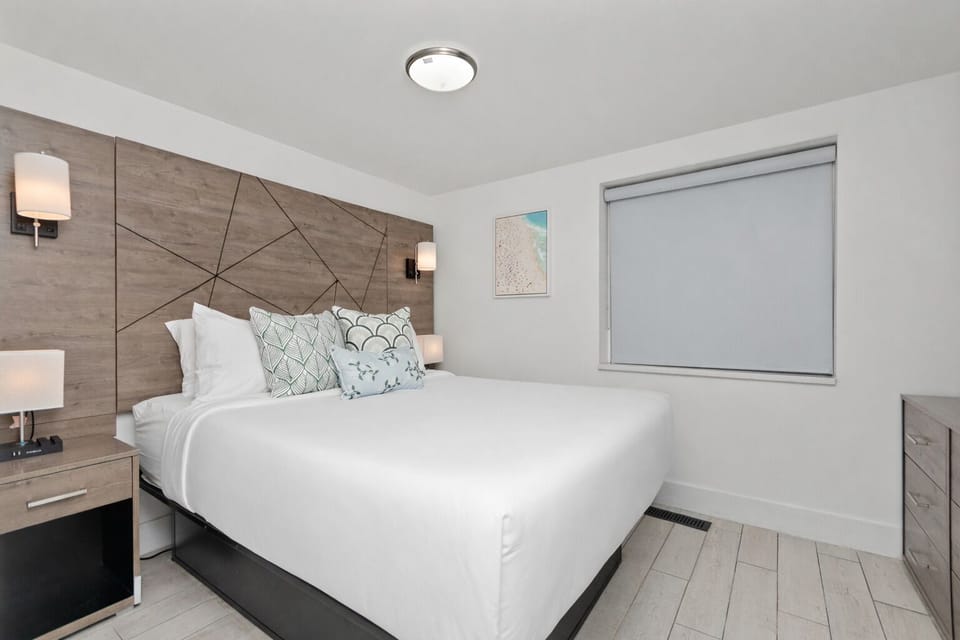 Primary bedroom in this two-bedroom suite offers a plush queen bed, coastal-inspired décor, crisp linens, and a bright, relaxing space ideal for a couple.