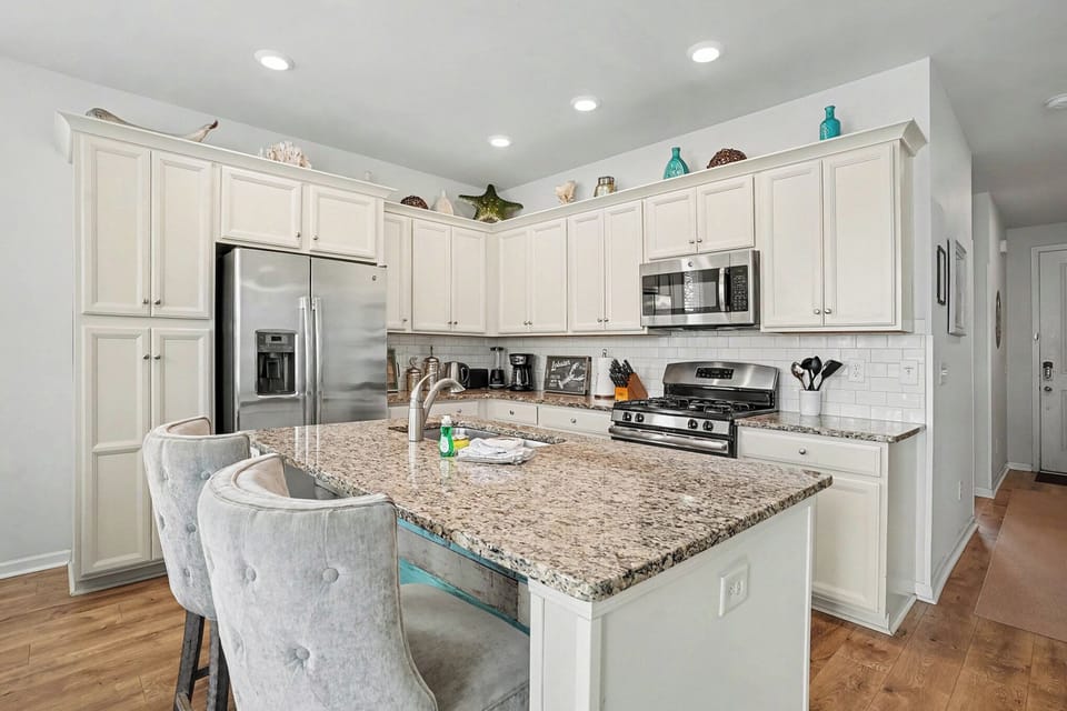 Coastal-style kitchen featuring granite countertops, stainless steel appliances, and ample prep space.