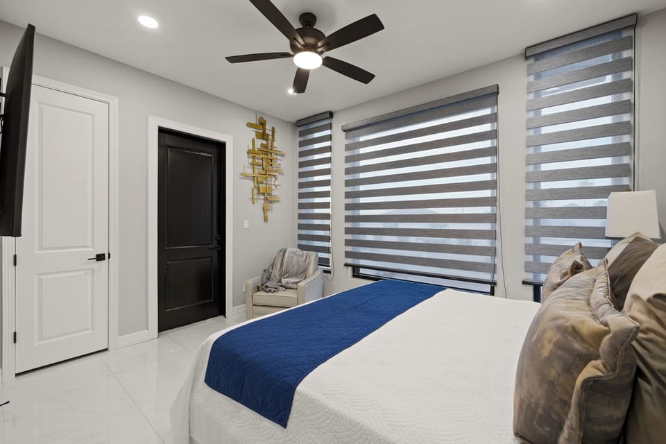 Fourth guest bedroom with a full bed, TV, and ample natural light.
