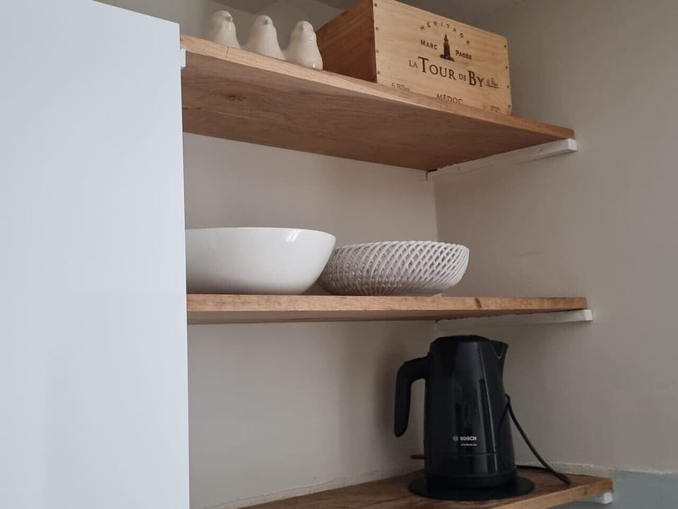 Cuisine toute équipée avec meuble de rangements, four, micro-onde, plaques de cuisson, hotte, lave-vaisselle, réfrigérateur, congélateur, table et chaises pour 4 personnes, bouilloire, machine à café, grille pain et ustensils de cuisine.