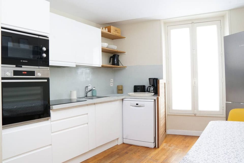 Cuisine toute équipée avec meuble de rangements, four, micro-onde, plaques de cuisson, hotte, lave-vaisselle, réfrigérateur, congélateur, table et chaises pour 4 personnes, bouilloire, machine à café, grille pain et ustensils de cuisine.