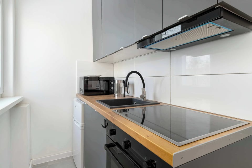 Modern kitchenette with base cabinets, black countertop, cooktop, and minimalist design.