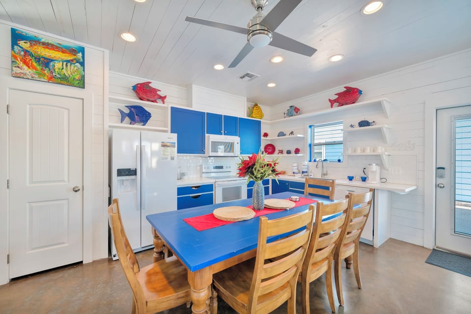 Your vibrant beach-themed kitchen invites you to cook with ocean-inspired blue cabinets, playful fish décor, and a sunny dining space perfect for shared meals.