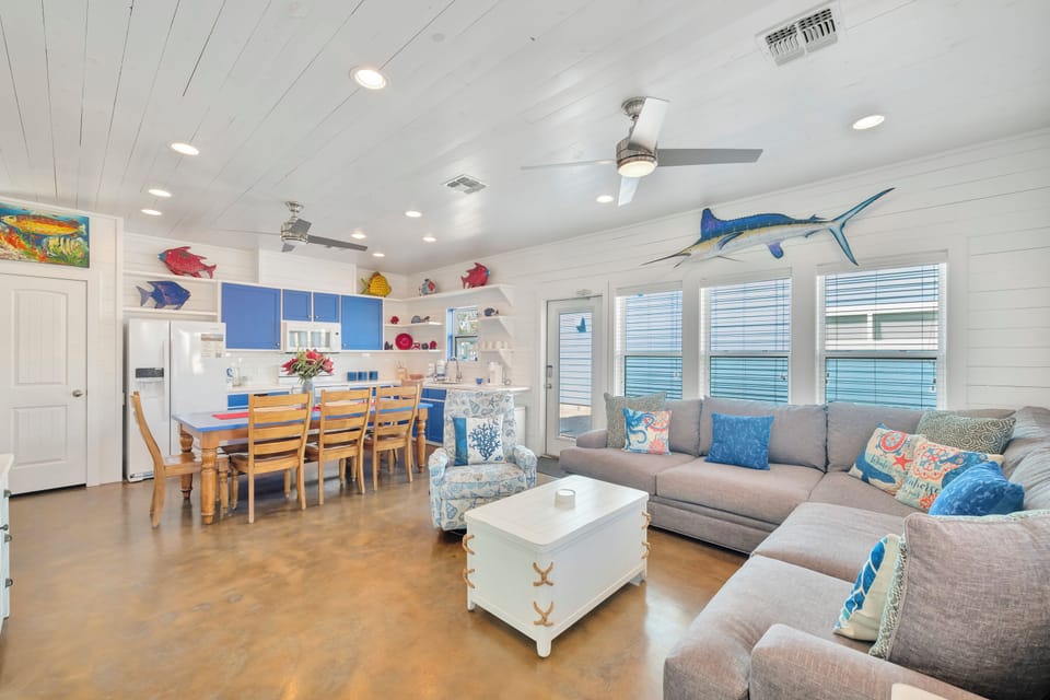 Relax in this coastal-themed living space where colorful fish art and nautical touches create your perfect beach getaway atmosphere.