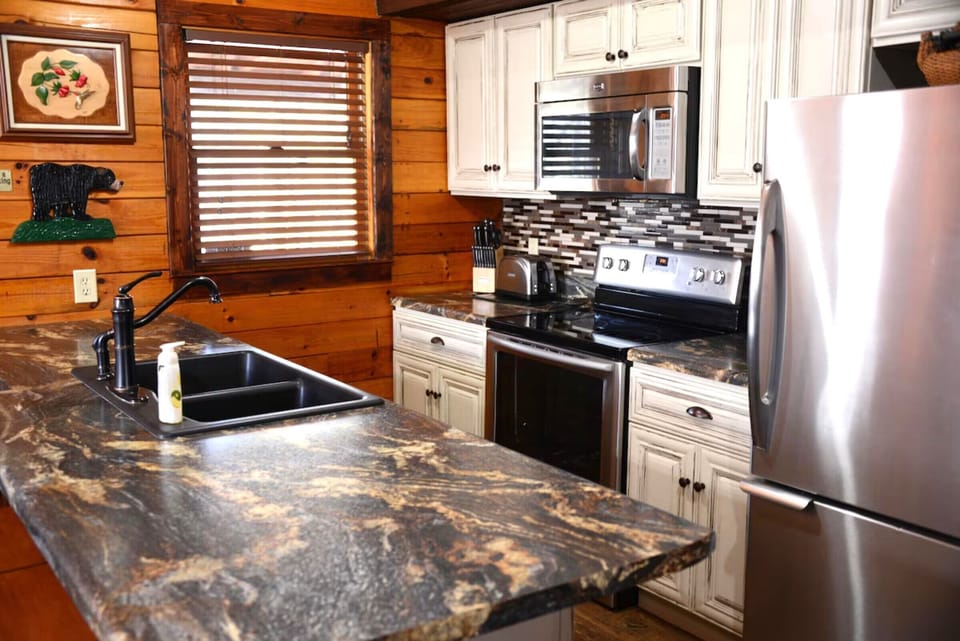 Your fully equipped cabin kitchen features granite countertops, stainless appliances, and warm wood walls for memorable mountain meals.