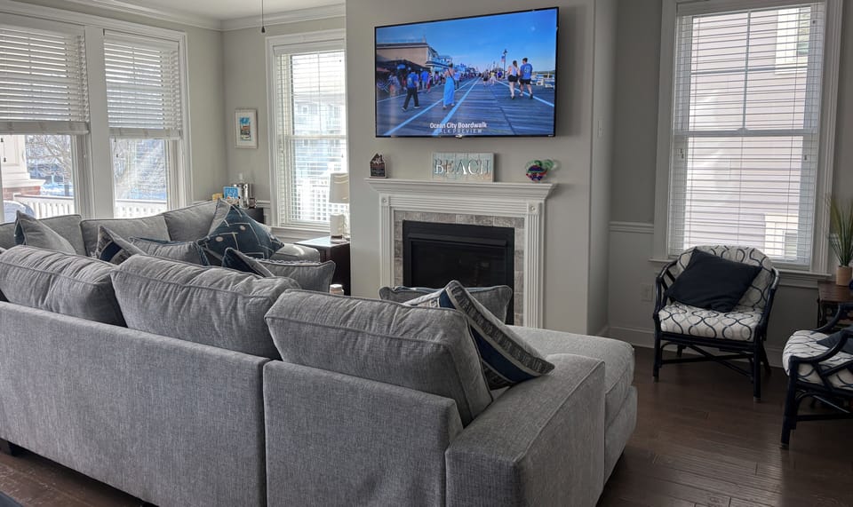 Living room with fireplace, large TV, wine fridge & new (2026) sectional.