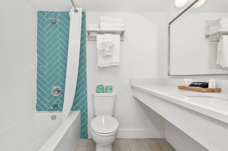 Full, modern bathroom with a shower and bathtub, toilet, and sink. Equipped with essential bathroom amenities including shampoo, conditioner, toothbrush, and fresh towels for a comfortable, hassle-free stay.