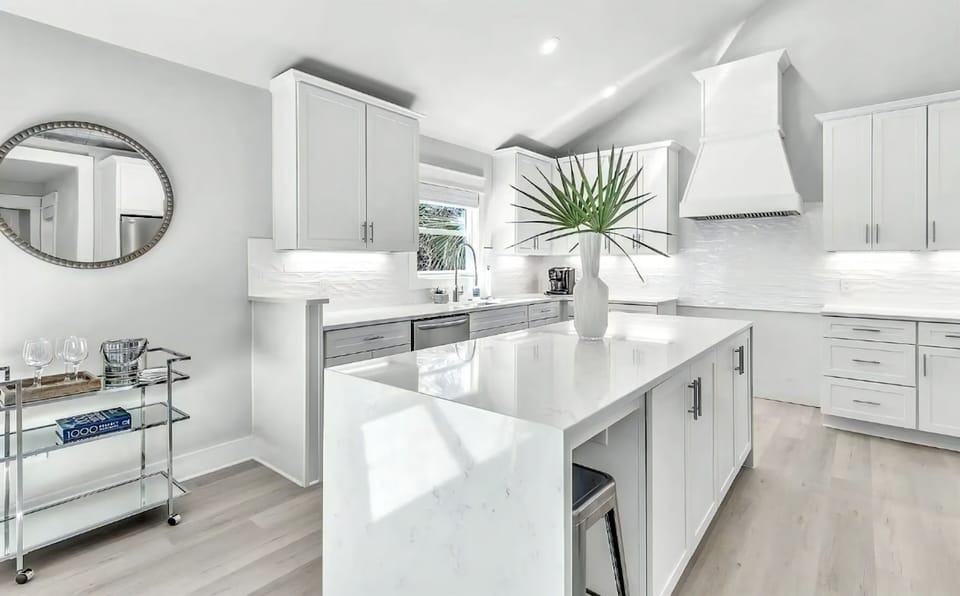Crisp white cabinetry, bar seating, and a waterfall island anchor this composed kitchen.