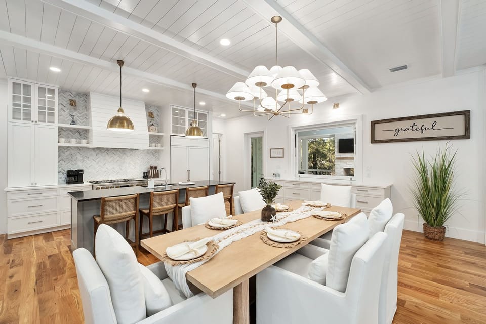 Your open-concept kitchen and dining area features gleaming white cabinetry, warm wood floors, and elegant lighting where memorable meals await.