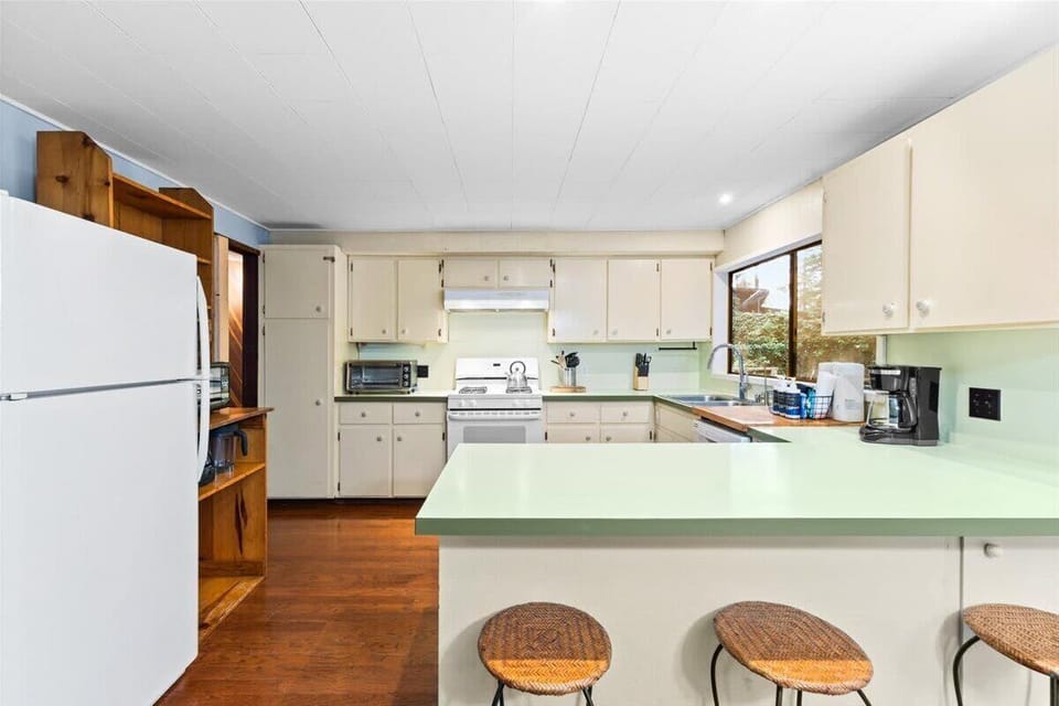 Fully equipped kitchen featuring a breakfast bar, garden window, and forest views.