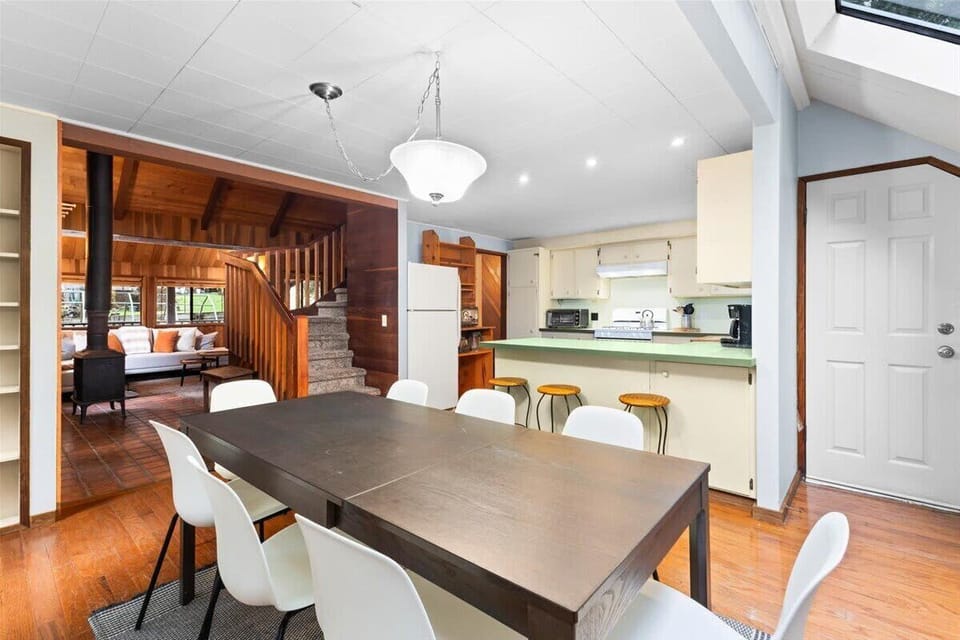 Bright dining area with forest views, skylights, and seating for 8 near the kitchen bar.