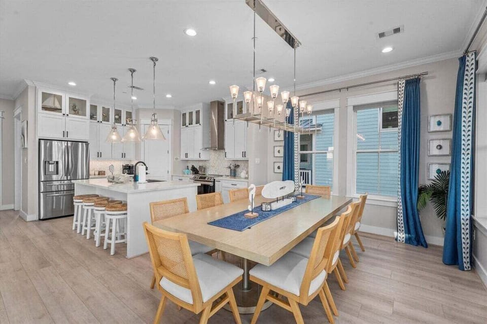 Large dining table with seating for big groups, statement chandelier, and open flow to kitchen.